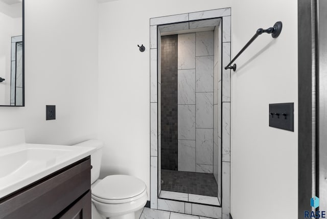 bathroom with a tile shower, vanity, and toilet