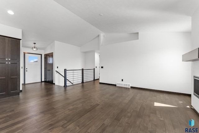 5413 E 64th St, Sioux Falls, SD 57108 - unfurnished living room with dark wood-style floors, visible vents, vaulted ceiling, and baseboards