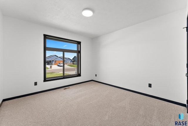 empty room with light colored carpet and a textured ceiling