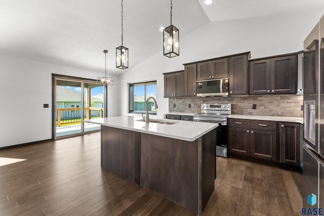 kitchen featuring appliances with stainless steel finishes, hanging light fixtures, an island with sink, dark hardwood / wood-style floors, and sink