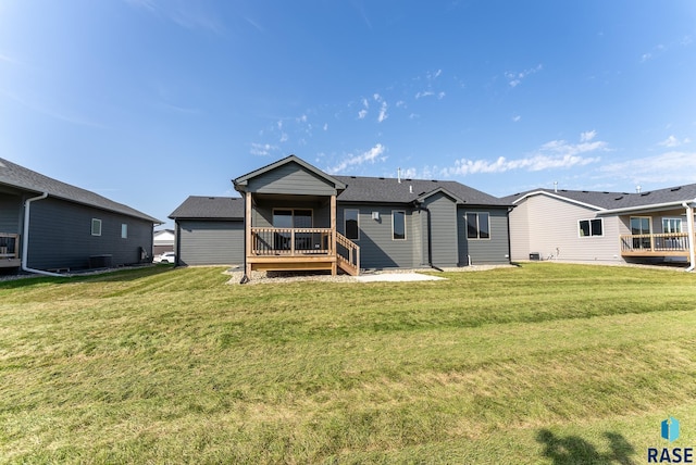 back of property featuring a deck and a lawn