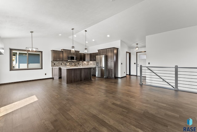 kitchen with lofted ceiling, hanging light fixtures, dark wood-type flooring, stainless steel appliances, and a center island