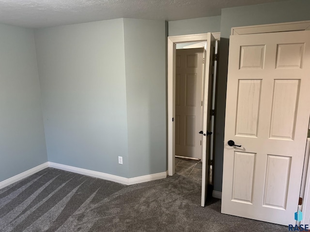 unfurnished bedroom featuring dark carpet and baseboards