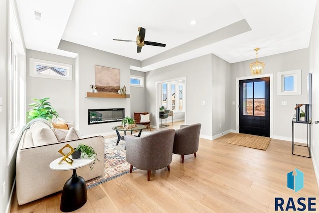 living room featuring ceiling fan with notable chandelier and light hardwood / wood-style floors