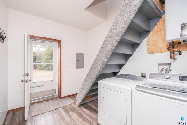 washroom with light hardwood / wood-style flooring, electric panel, tankless water heater, and washing machine and dryer