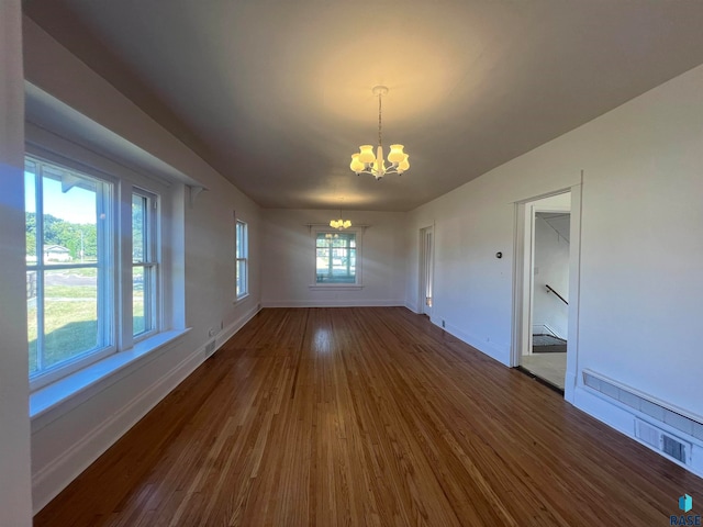 unfurnished dining area with dark wood-type flooring and a notable chandelier