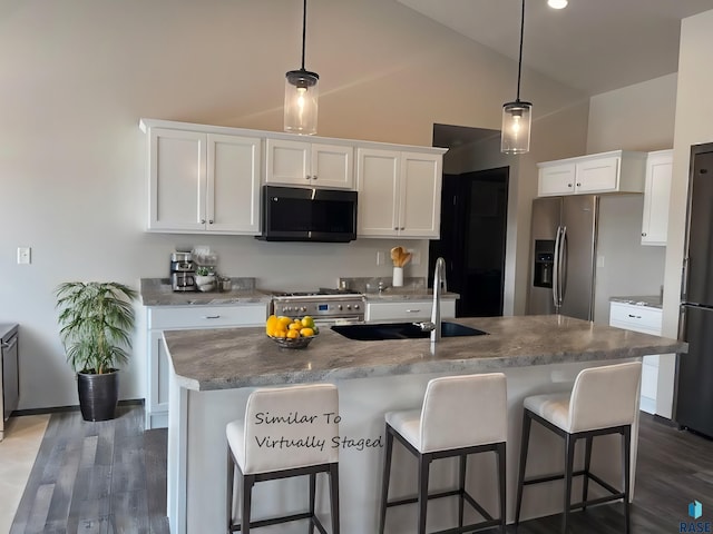 kitchen featuring pendant lighting, white cabinetry, dark hardwood / wood-style floors, a center island with sink, and stainless steel appliances