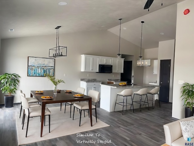 dining room with sink, vaulted ceiling, and dark wood-type flooring