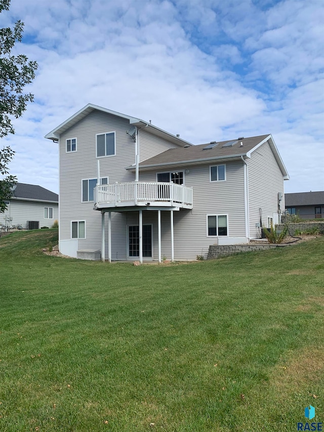 back of house featuring a lawn and a balcony