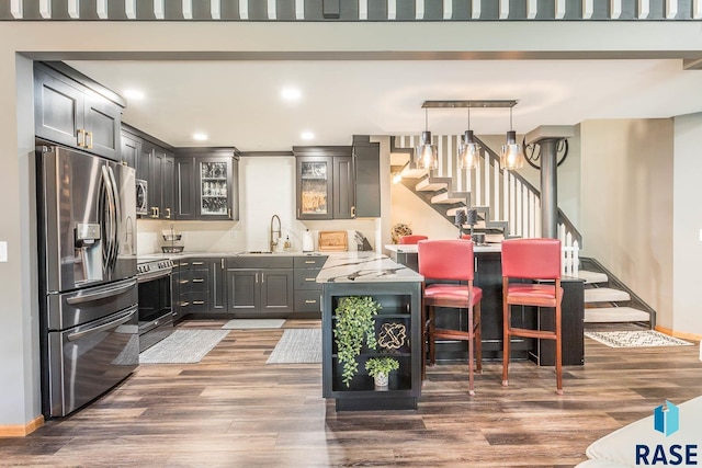 kitchen with light stone counters, stainless steel appliances, hanging light fixtures, and dark wood-type flooring