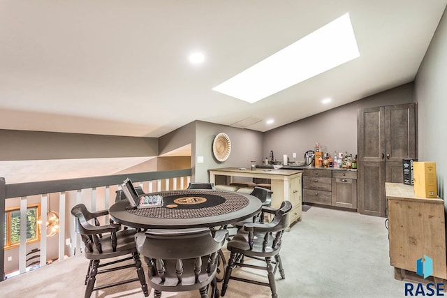 carpeted dining room featuring vaulted ceiling with skylight