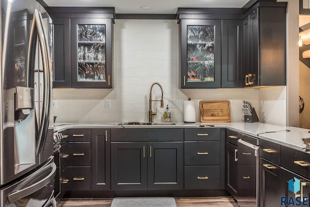 kitchen with light stone counters, hardwood / wood-style flooring, stainless steel fridge, and sink