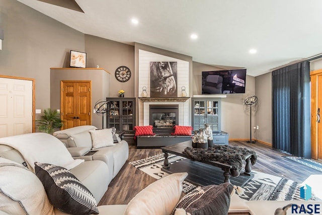 living room featuring a large fireplace, lofted ceiling, and hardwood / wood-style flooring