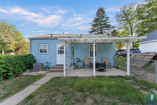 back of property with a lawn, a pergola, central AC, and a patio area