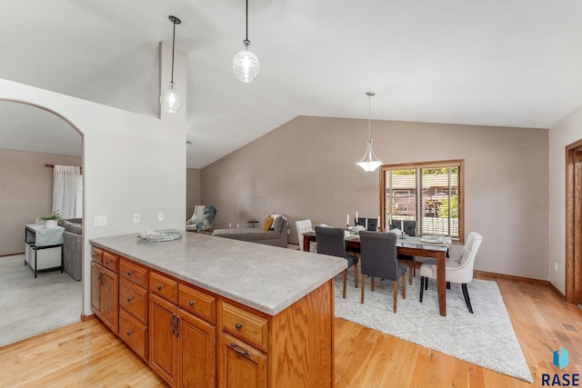 kitchen with light hardwood / wood-style flooring, vaulted ceiling, and decorative light fixtures