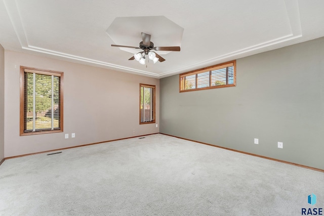 carpeted empty room featuring ceiling fan and a raised ceiling