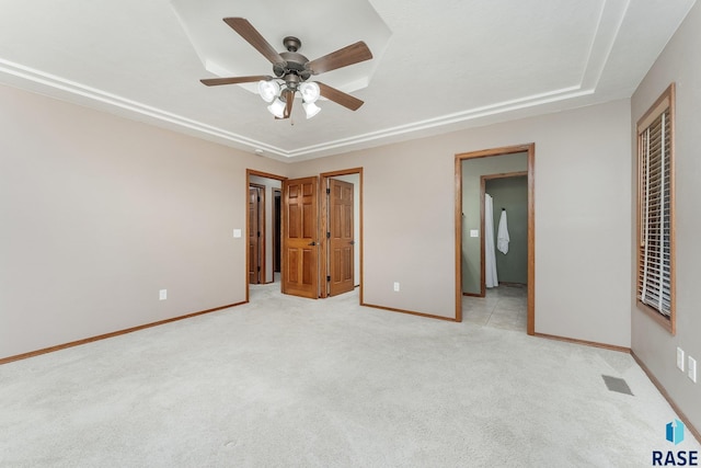 unfurnished bedroom with a closet, light colored carpet, ceiling fan, and ensuite bathroom