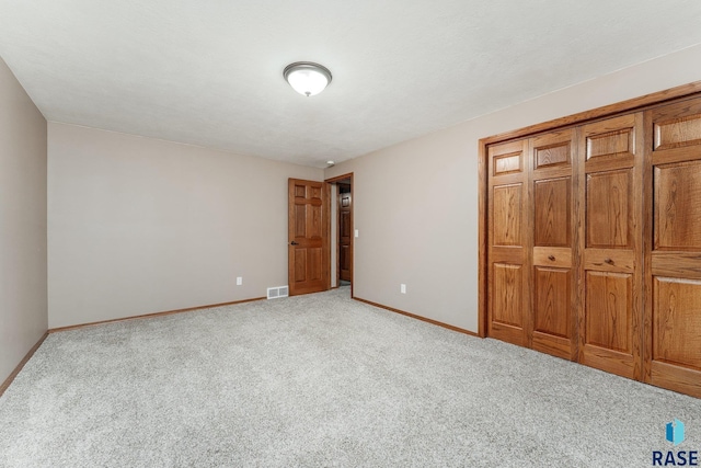 unfurnished bedroom featuring a closet and light carpet