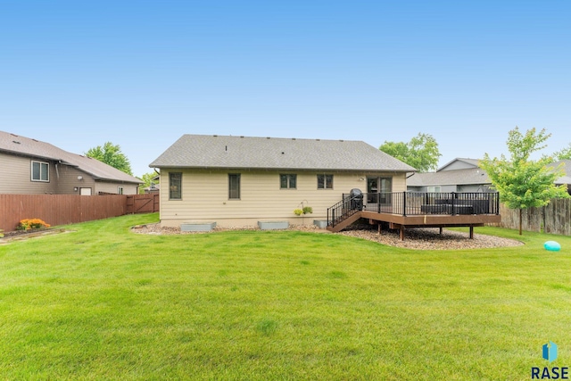 rear view of property featuring a wooden deck and a lawn