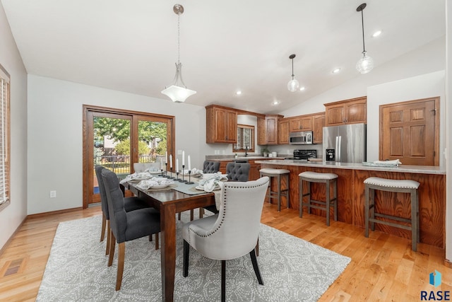 dining area featuring light wood-type flooring, lofted ceiling, and sink