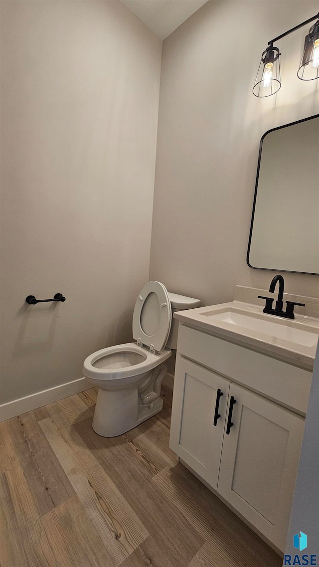 bathroom with wood-type flooring, vanity, and toilet