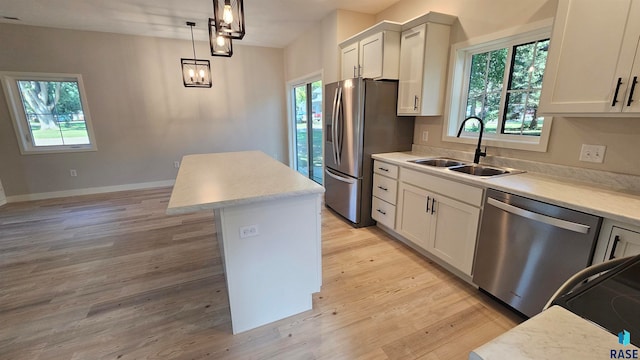 kitchen featuring pendant lighting, sink, a kitchen island, stainless steel appliances, and light wood-type flooring