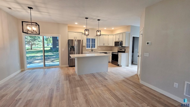 kitchen with pendant lighting, a center island, sink, white cabinets, and appliances with stainless steel finishes