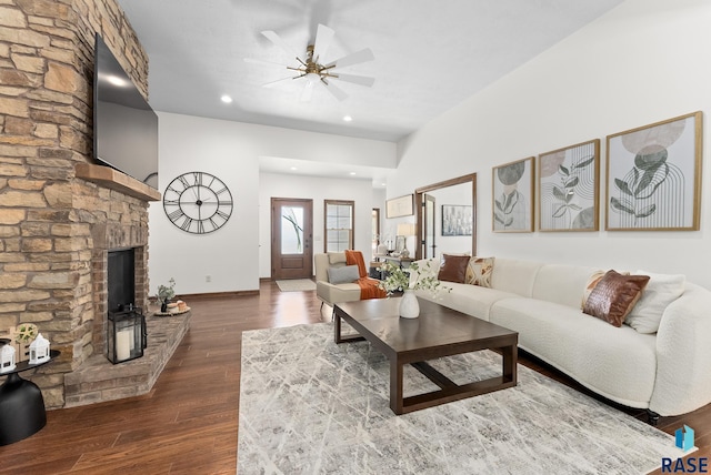 living room featuring a fireplace, ceiling fan, and dark wood-type flooring