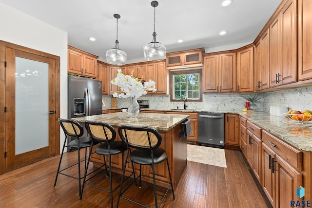 kitchen featuring pendant lighting, sink, a kitchen island, dark wood-type flooring, and stainless steel appliances