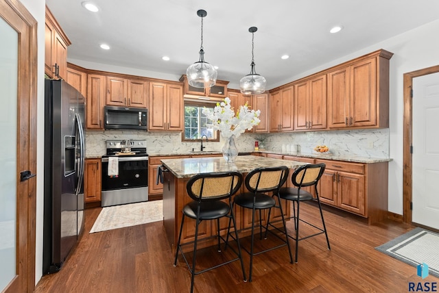 kitchen featuring a center island, dark wood-type flooring, sink, appliances with stainless steel finishes, and light stone countertops