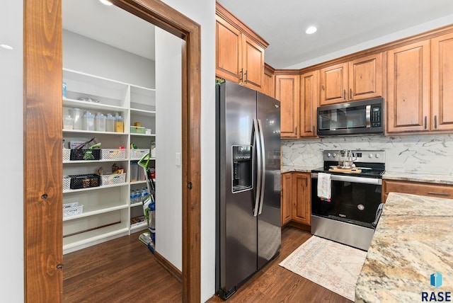 kitchen with backsplash, light stone countertops, stainless steel appliances, and dark hardwood / wood-style flooring