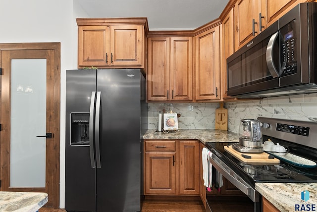 kitchen with light stone counters, appliances with stainless steel finishes, backsplash, and hardwood / wood-style floors