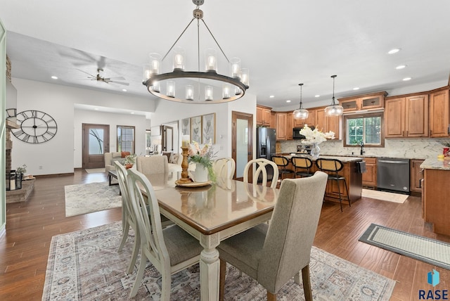 dining space with ceiling fan with notable chandelier, dark hardwood / wood-style flooring, and sink