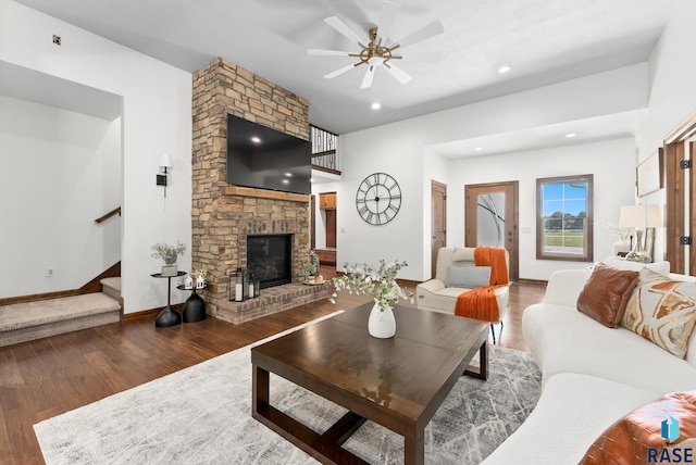 living room with ceiling fan, a stone fireplace, and dark hardwood / wood-style flooring