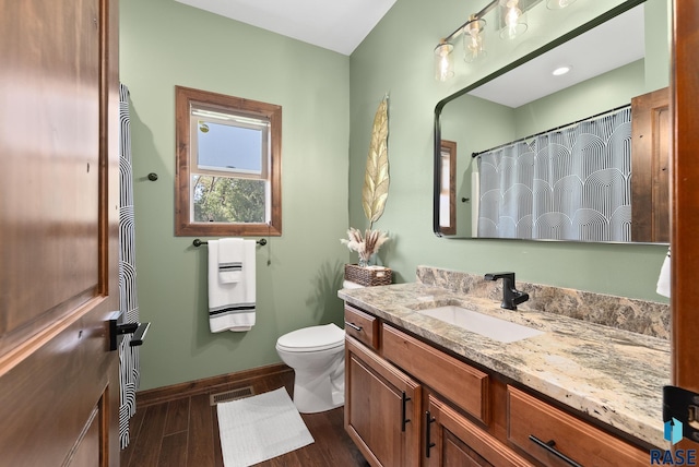 bathroom with vanity, toilet, heating unit, and hardwood / wood-style flooring