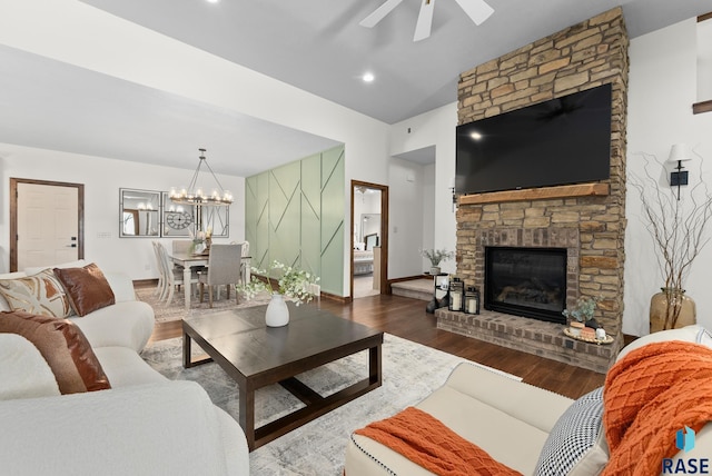 living room with ceiling fan with notable chandelier, wood-type flooring, vaulted ceiling, and a fireplace