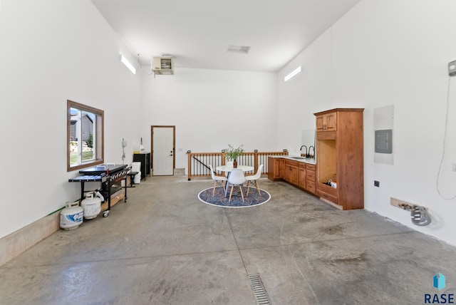 misc room featuring a high ceiling, sink, concrete flooring, and electric panel