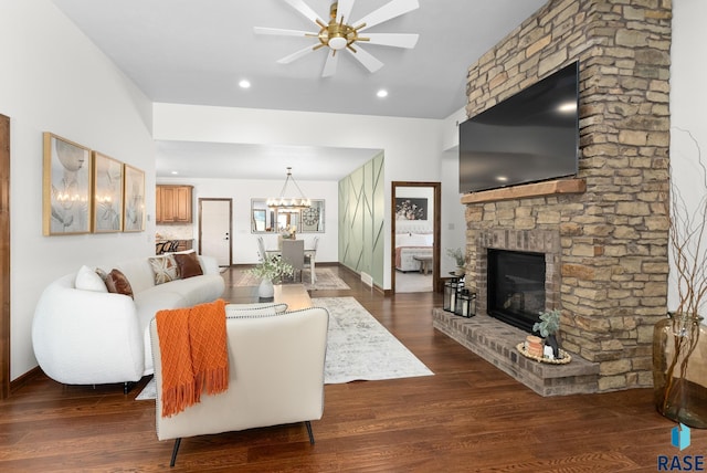 living room featuring ceiling fan with notable chandelier, a fireplace, and dark hardwood / wood-style floors