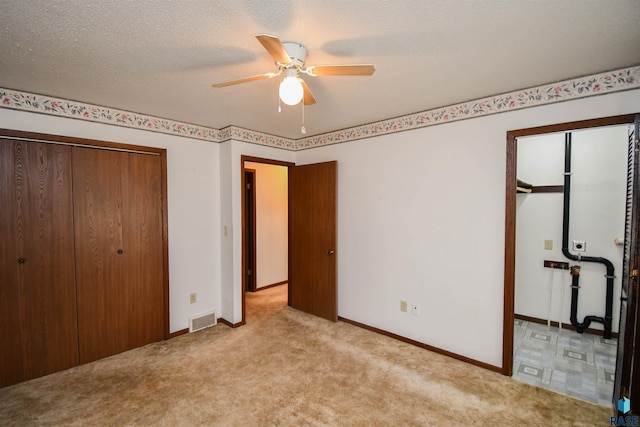 unfurnished bedroom featuring ceiling fan, light colored carpet, and a textured ceiling