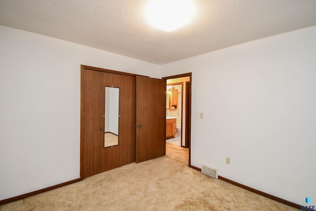 unfurnished bedroom with light colored carpet, a textured ceiling, and a closet