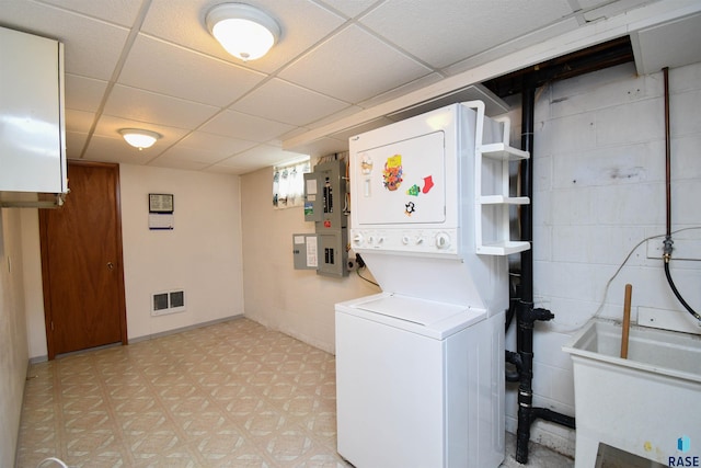 clothes washing area with stacked washer / dryer, electric panel, and sink