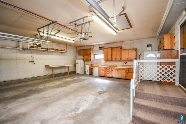 garage with white refrigerator, a garage door opener, and a workshop area