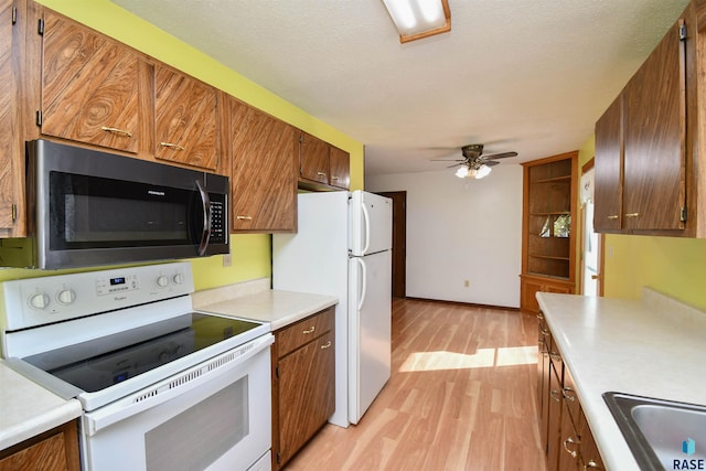 kitchen featuring white appliances, light hardwood / wood-style floors, ceiling fan, and a textured ceiling