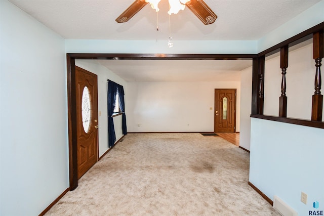 carpeted foyer entrance featuring ceiling fan and a textured ceiling