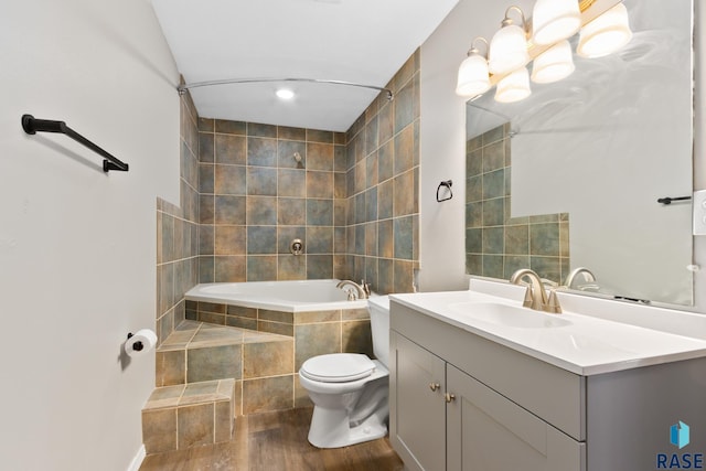 full bathroom featuring hardwood / wood-style floors, vanity, toilet, and tiled shower / bath