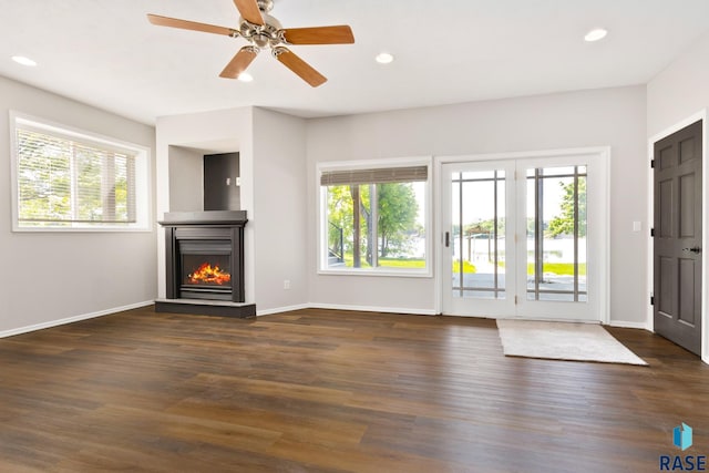 unfurnished living room featuring dark hardwood / wood-style floors, ceiling fan, and plenty of natural light