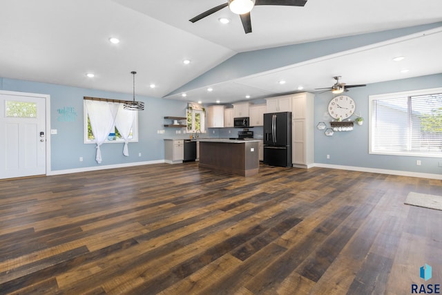 interior space with ceiling fan, hanging light fixtures, a kitchen island, black appliances, and vaulted ceiling