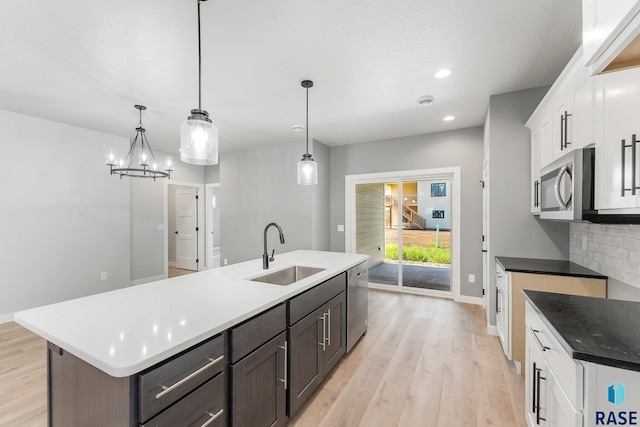 kitchen featuring appliances with stainless steel finishes, a center island with sink, white cabinetry, and sink