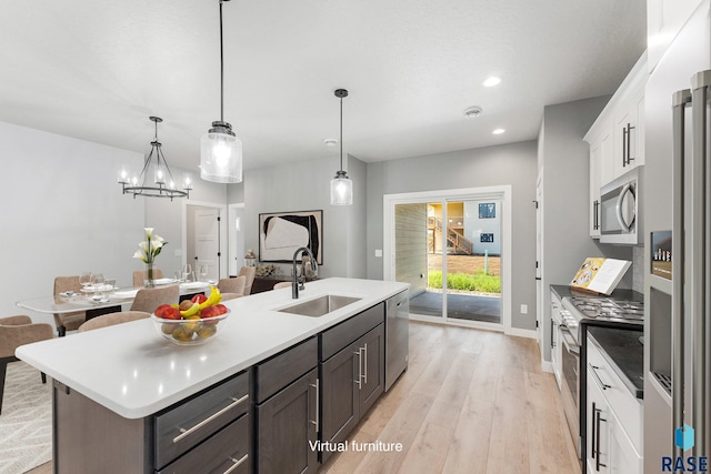 kitchen with light hardwood / wood-style floors, an island with sink, white cabinets, stainless steel appliances, and sink