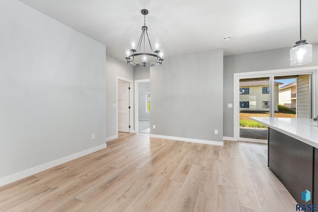 unfurnished dining area featuring an inviting chandelier and light wood-type flooring